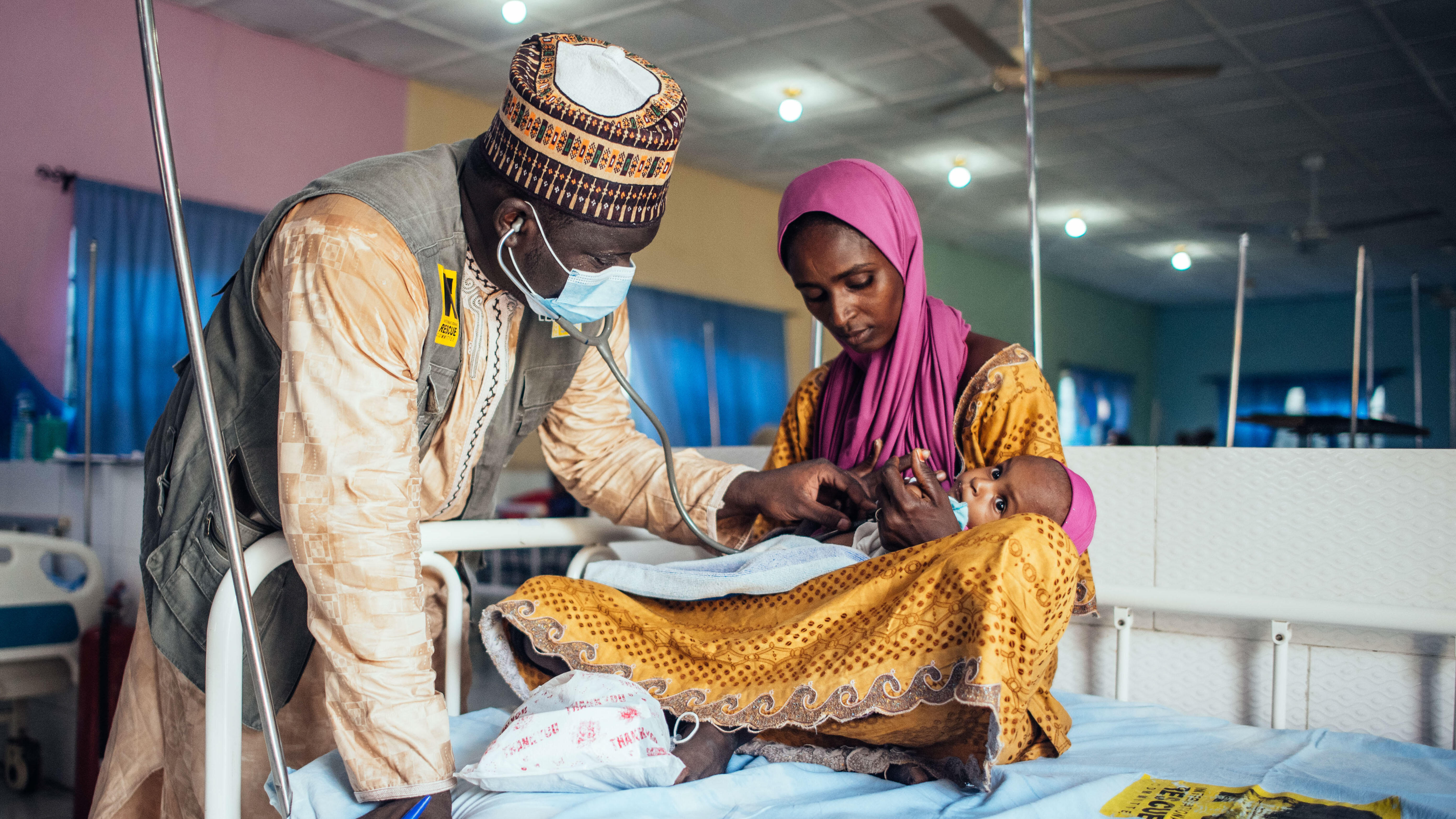 An IRC health officer screens a child at a health facility.